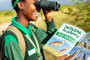 DALL·E 2024-09-17 12.14.51 – A happy Eco Ranger student in the field, studying wildlife with a SkillsLink Academy textbook. The student, a young adult of African descent, is weari